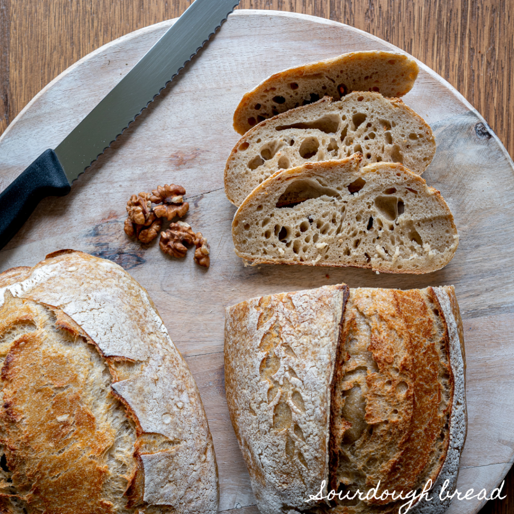 Image of sliced sourdough bread on cutting board that it sitting on a table.