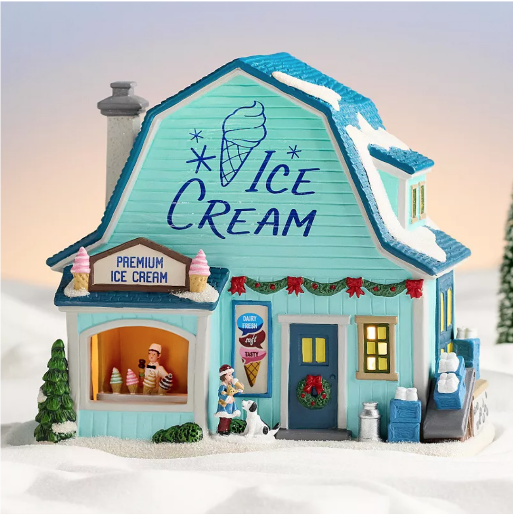 Image of Christmas village house that looks like a charming ice cream parlor. Color is mint green, says "ice cream", and "premium ice cream" Boy is in the window selling ice cream cones and little girls is out front of the ice cream shop with a dog. 