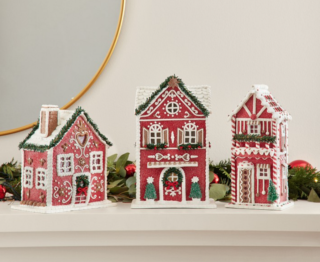 Image of 3 Christmas village houses on sale. All 3 houses are red with white piping and trim (looks like gingerbread houses). Houses are on mantel with garland.