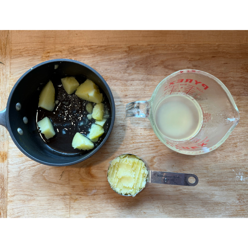 Image of small sauce pan with potato and mashed potato in 1/4 measuring cup. Items are on a wooden cutting board. Text says "lightly mash 1/4 cup potato and add to wet ingredients." 