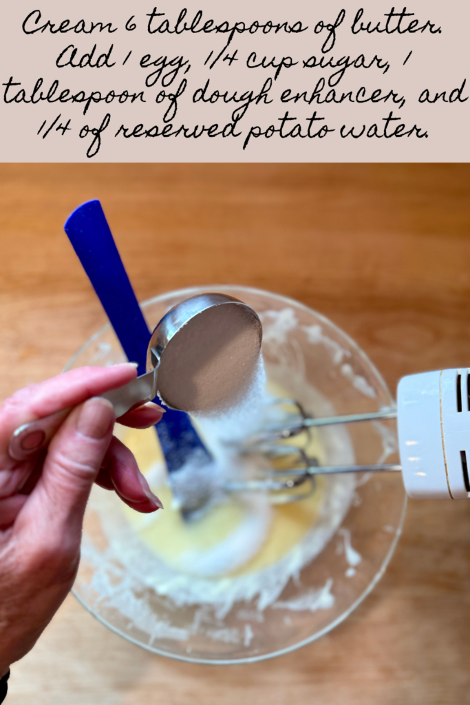 Image of woman pouring sugar into glass medium bowl to combine with rest of wet ingredients for easy bread wreath recipe. Text says "cream 6 tablespoons of butter with a hand mixer on medium speed. Add 1 egg, 1/4 cup sugar, 1 tablespoon of dough enhancer, and 1/4 of reserved potato water. Blend until it's just combined."