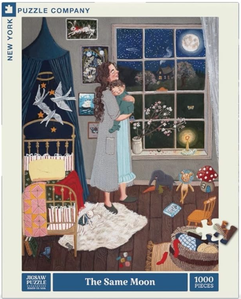 Picture of 1000 piece puzzle called "The Same Moon". Puzzle is of a mother wearing a nightgown and bathroom while holding a toddler in pajamas during the night. They are in  the baby's room with a bed, toys, and artwork hung on the walls.