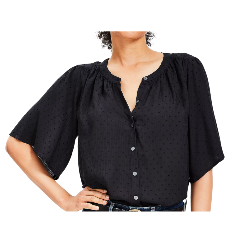 teacher outfit ideas. Image of woman wearing a black flutter sleeve blouse with her hand on her hip.