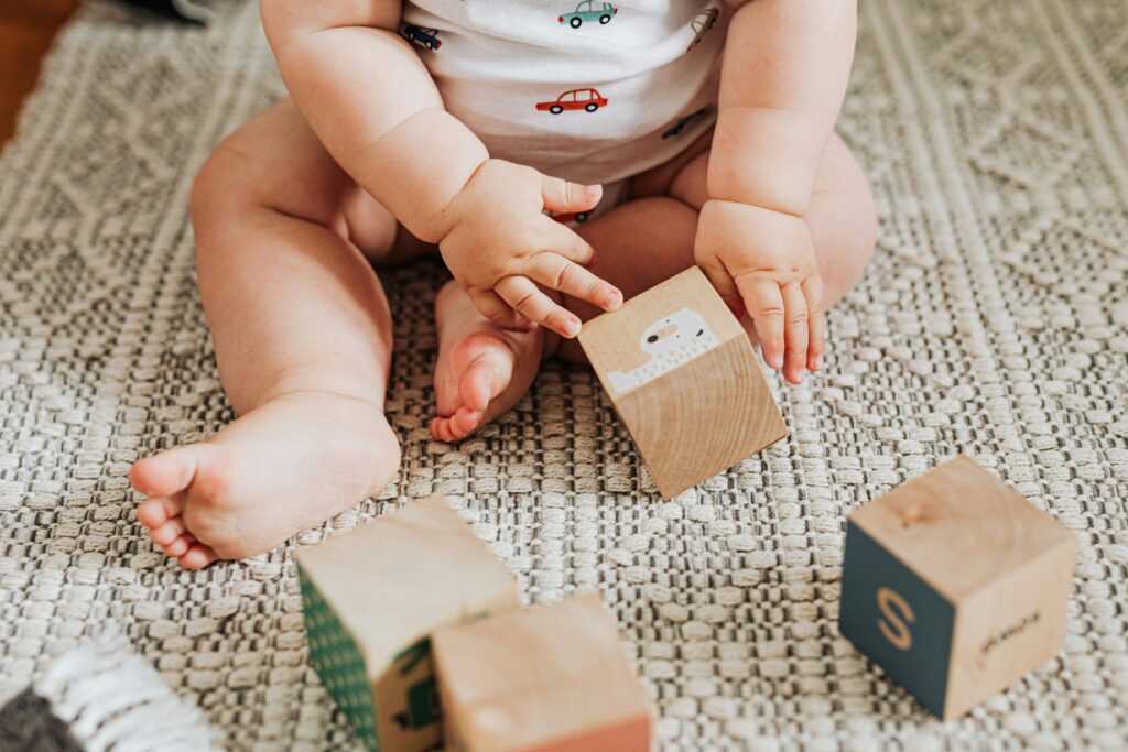 baby registry items. Image of baby playing with wooden blocks on rug.