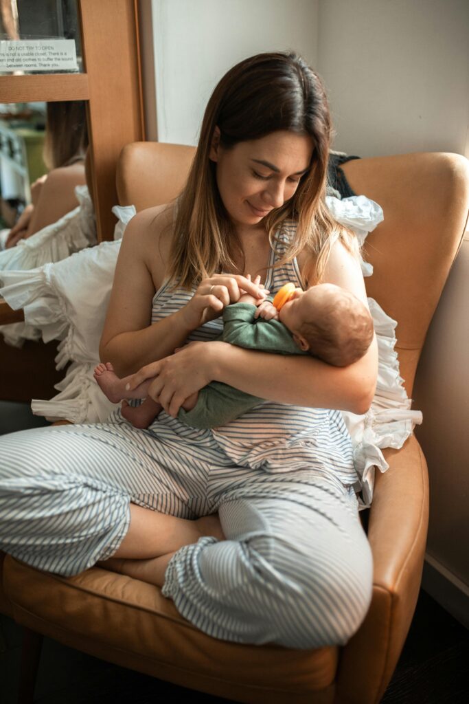 baby registry must haves Amazon. Image of women sitting in leather chair holding a baby.