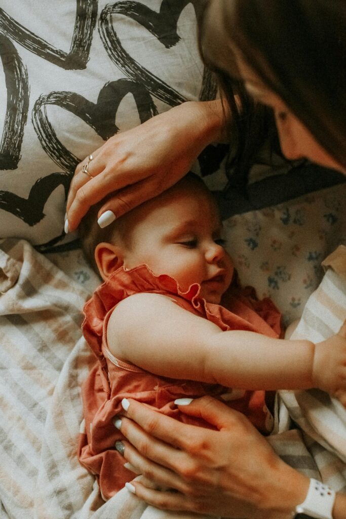 baby registry must haves checklist. Image of baby laying next to mom in bed.