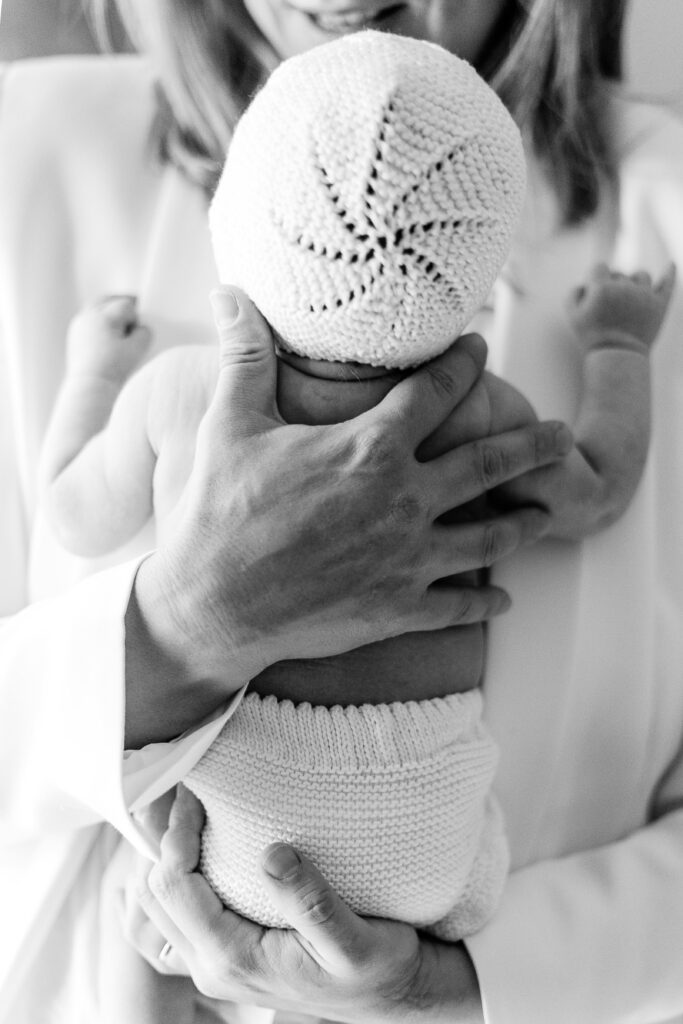 best baby registry must haves checklist. Black and white image of mom holding baby in a white knit hat.
